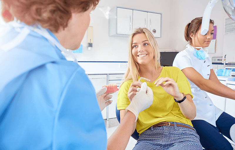 Young woman patient smiling as she speaks with her dentist